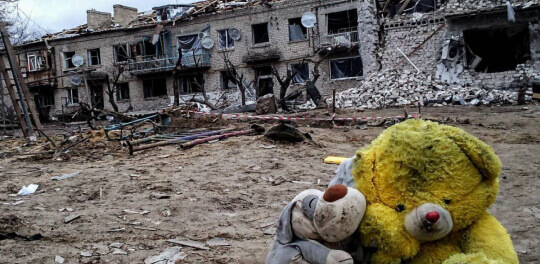 Детские игрушки на фоне разбомбленного дома